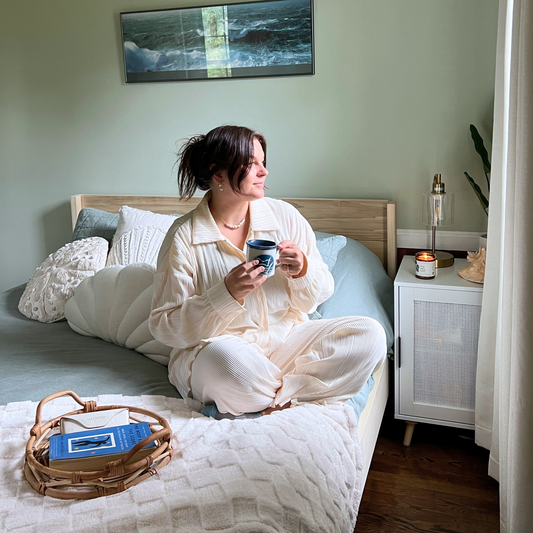 Woman drinking tee while sitting on The Sequoia Bed
