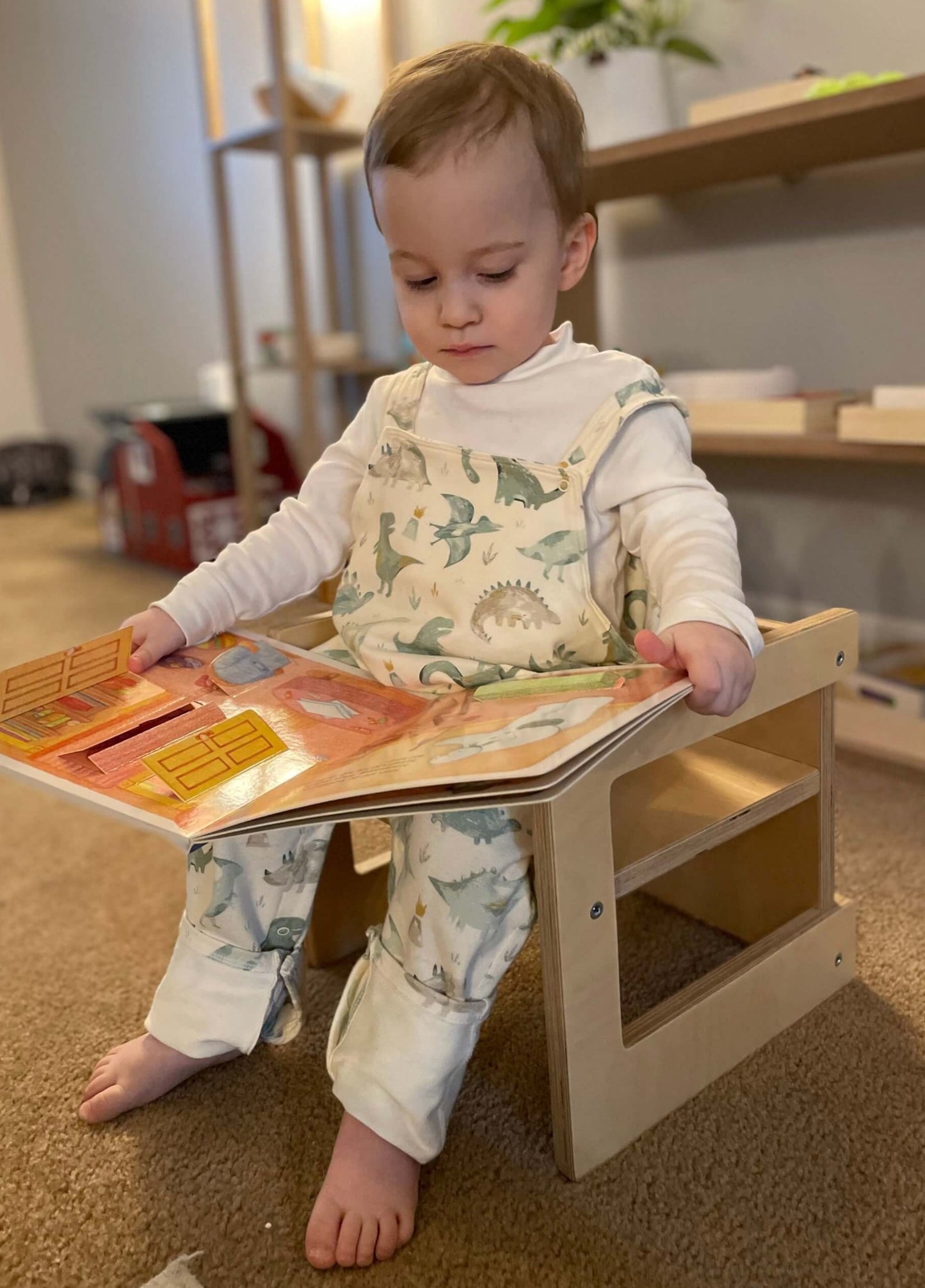 A toddler reading a book on a Montessori Cube Chair