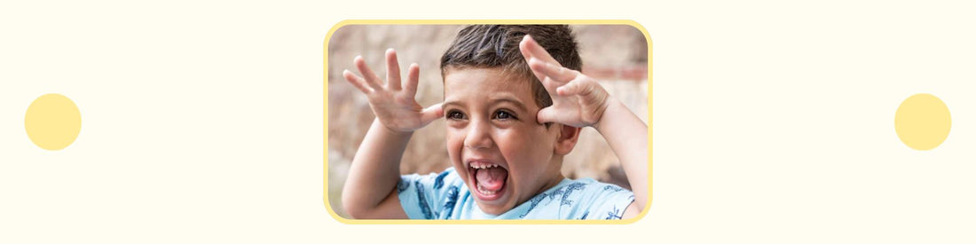 child holding hands up to head and making goofy facial expression