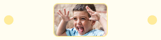 child holding hands up to head and making goofy facial expression
