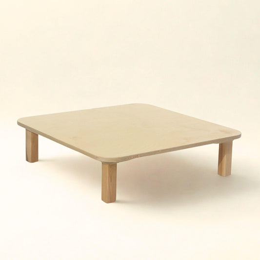 Toddler sitting at montessori toddler table made out of wood.