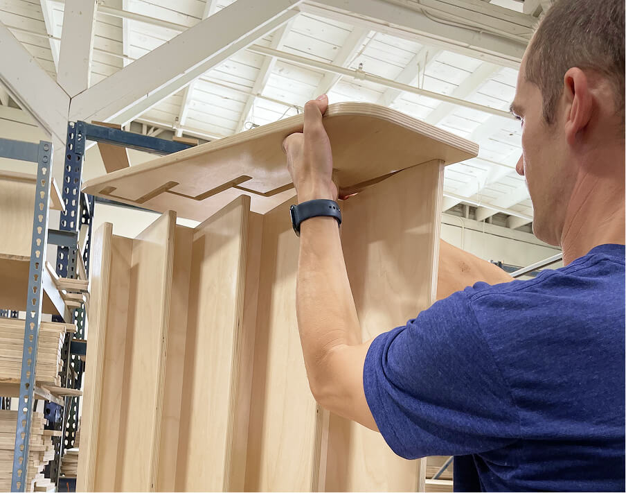 Person assembling a wooden shelf in a warehouse setting