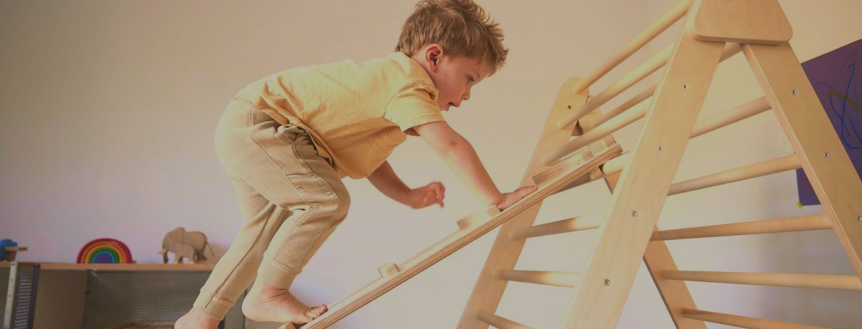 Child climbing a wooden pikler ladder indoors
