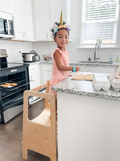 A child using the toddler learning tower in the kitchen