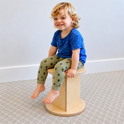 child sitting on wooden stool