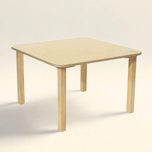 Toddler sitting at montessori toddler table made out of wood.