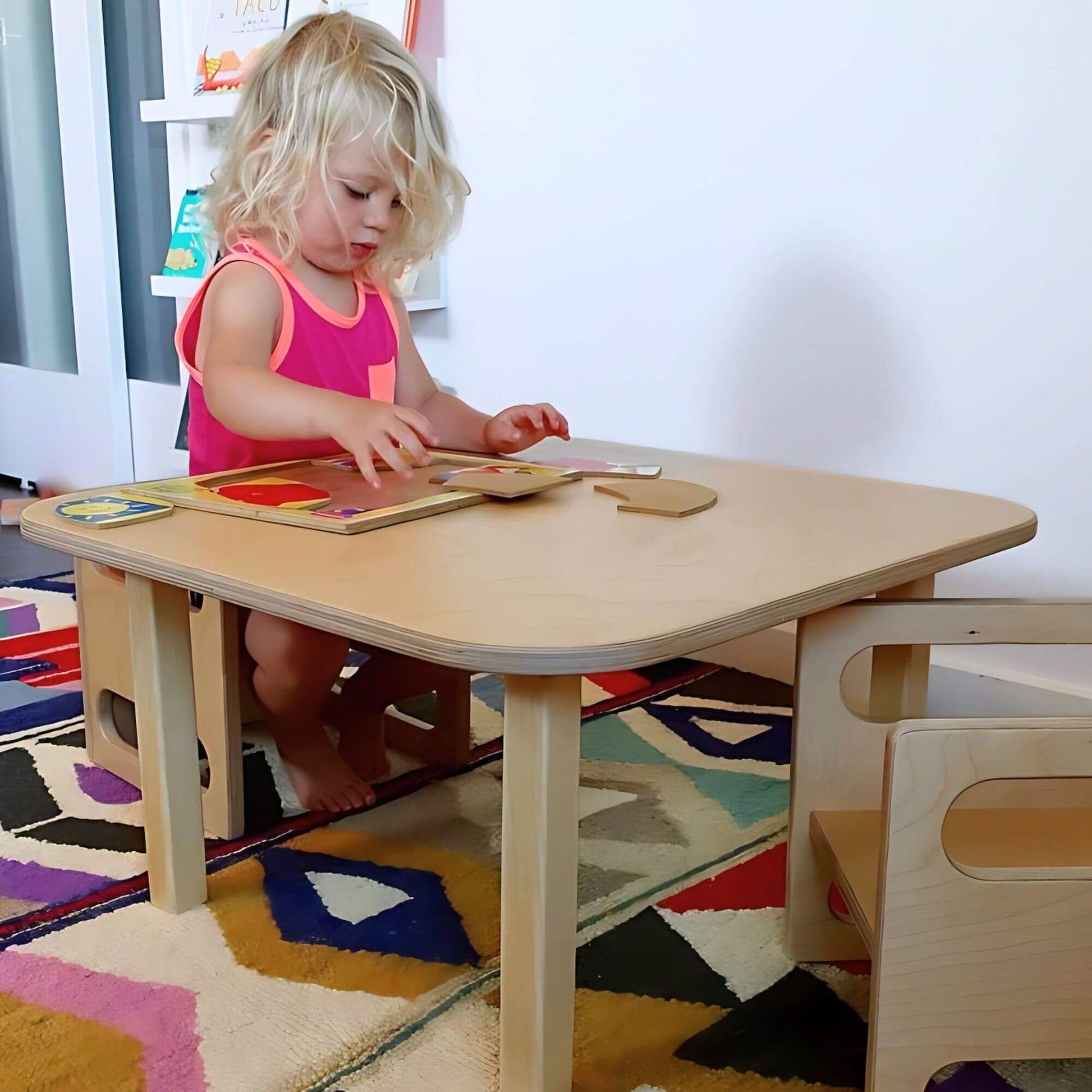 Toddler sitting at montessori toddler table made out of wood.