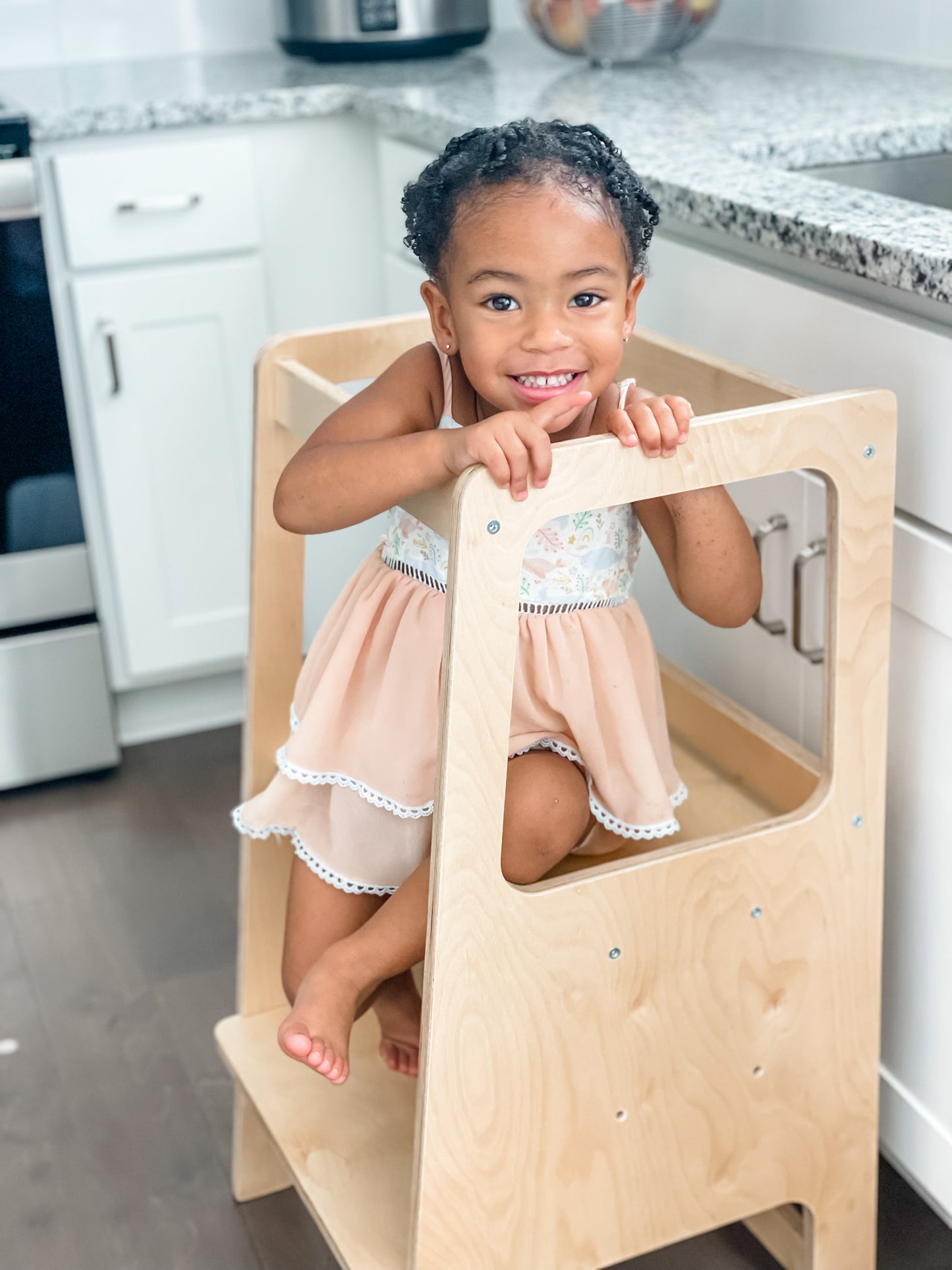 A child sitting on the toddler learning tower