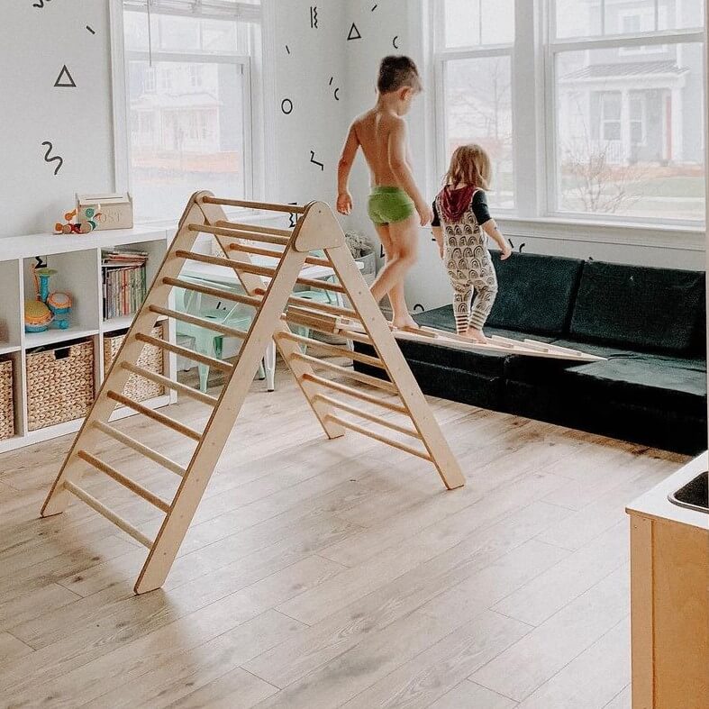 two children walking on ramp across climbing triangle