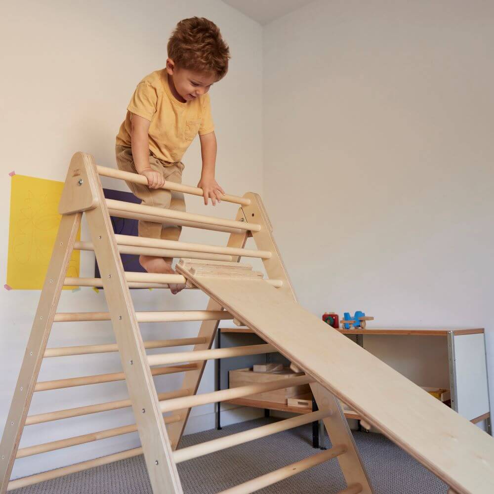 Toddler climbing on top of large pikler triangle