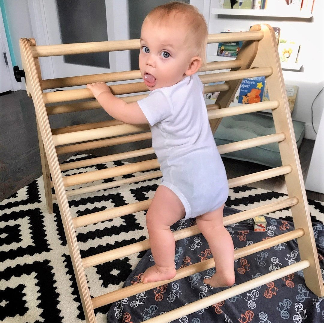 toddler learning how to pull himself up on a Montessori climbing triangle AKA best Pikler triangle