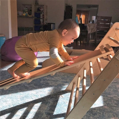 Baby climbing on pikler triangle ramp to work on their gross motor development.