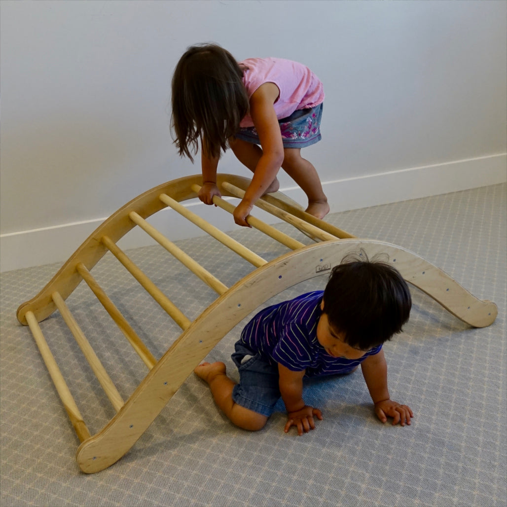 A girl climbs over the pikler arch, and her brother crawls underneath.  How versatile!